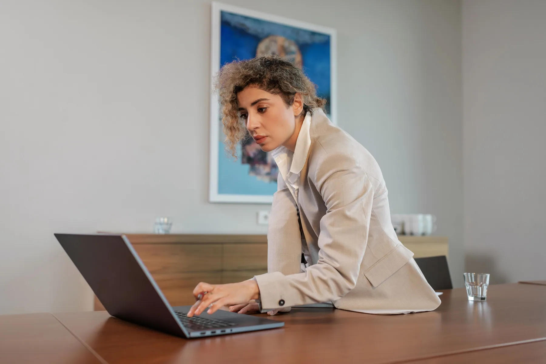 A professional woman working on her laptop in a naturally lit workspace