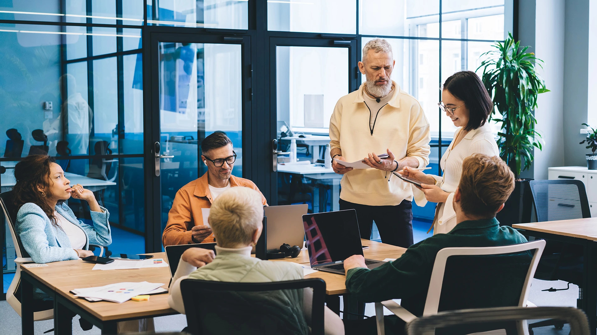 Colleagues discussing a project around a meeting table in a contemporary office